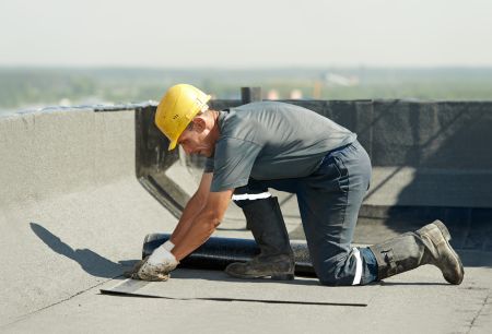 A roofing professional repairing a leak on a large commercial building.